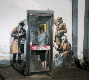 One of Banksys best known works of three men wearing sunglasses and using listening devices to snoop on a telephone box near GCHQ in Cheltenham